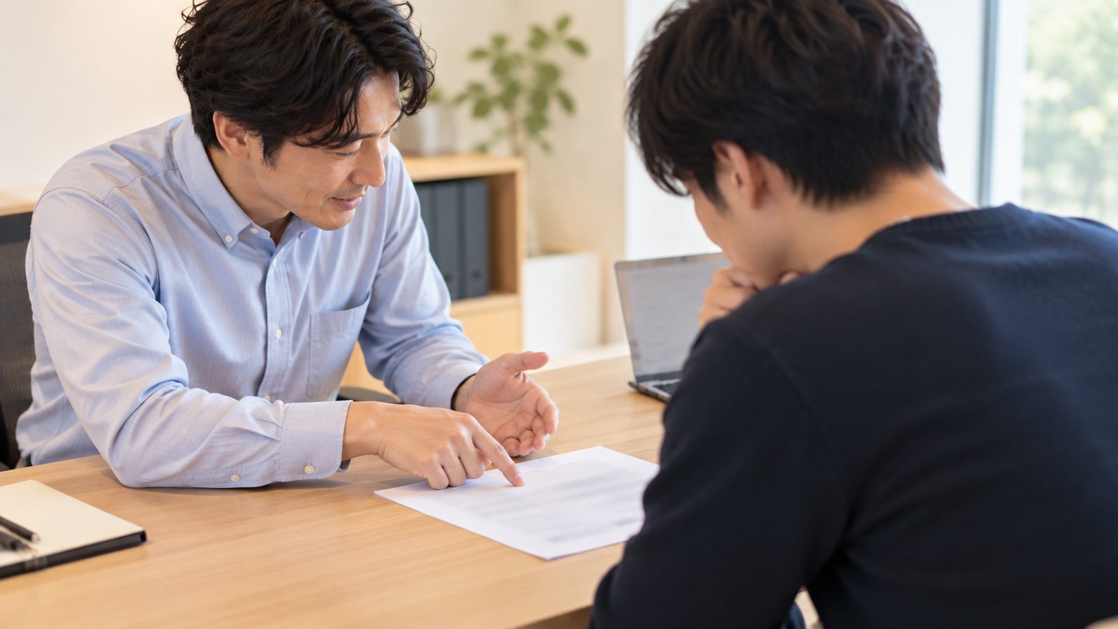 相談席で白紙の試算表を指して説明する担当者と、それを聞く人